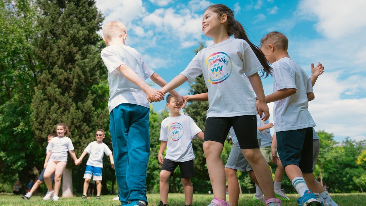 Happy children playing and holding hands outdoors in a sunny park.